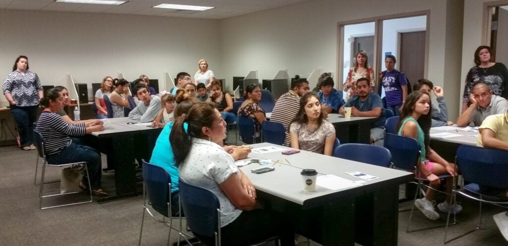 A group of community members listens to a presentation on college preparedness presented by the ECU Counselor Education Program and AMEXCAN.