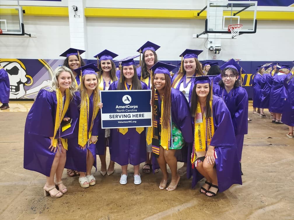 Graduates pose with AmeriCorps sign