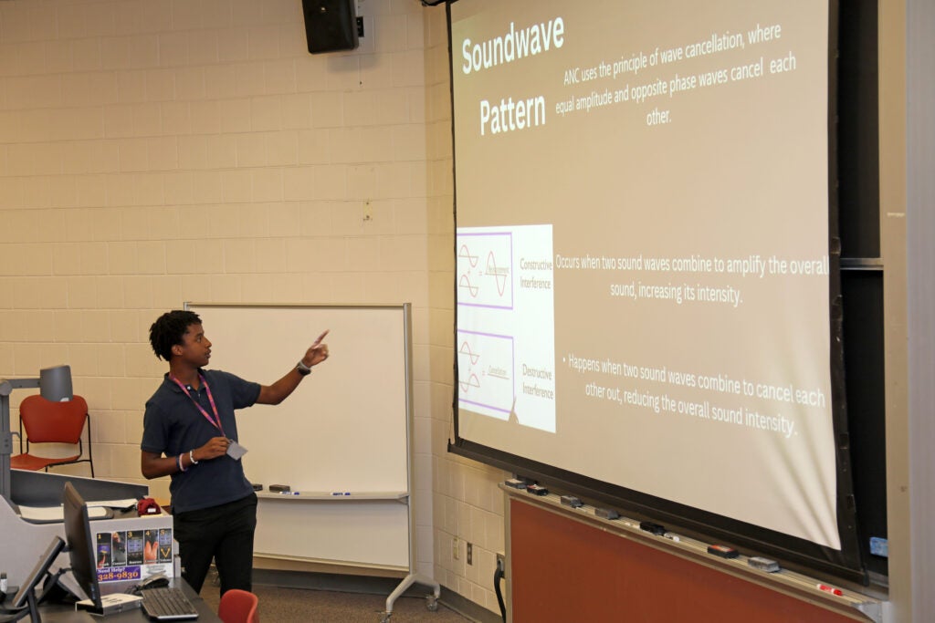 Summer Ventures student presenting research and pointing to a PowerPoint slide