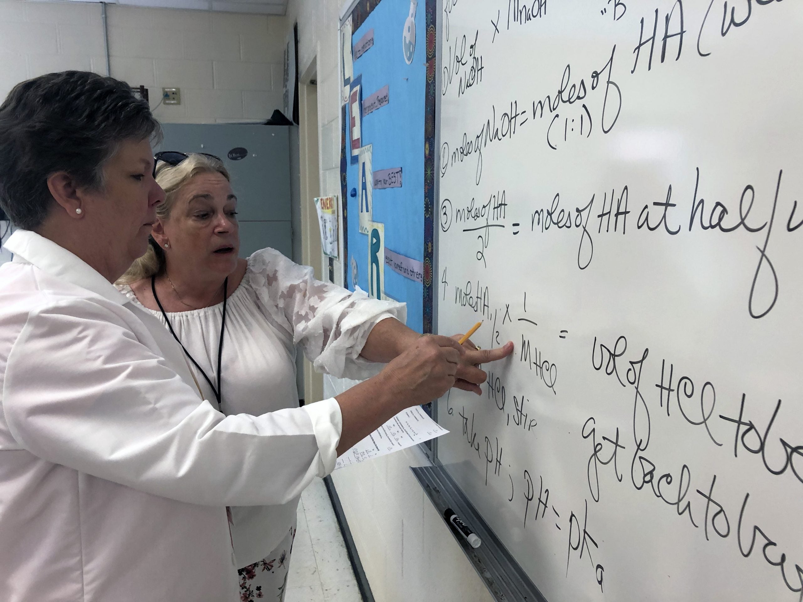 Instructor explains equation on whiteboard