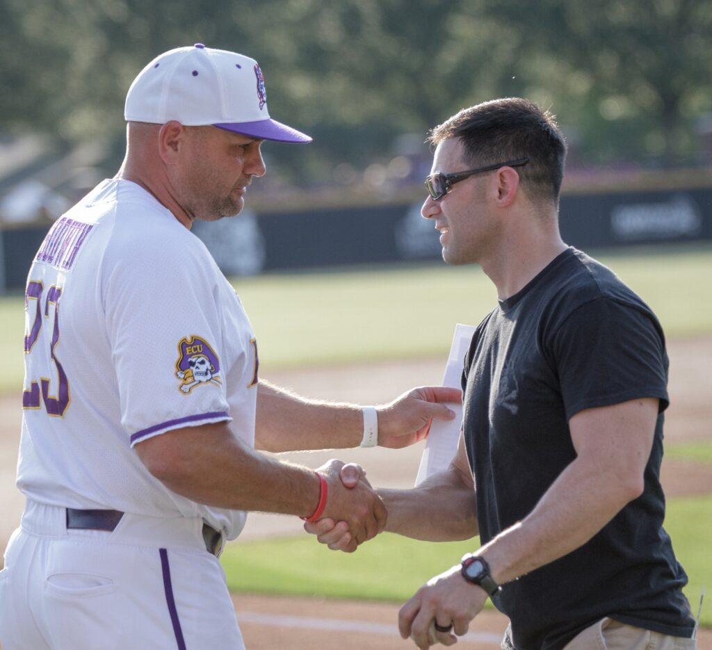 Ybarra shakes hands with ECU Baseball head coach Cliff Godwin after throwing out the first pitch on Friday, May 11. 