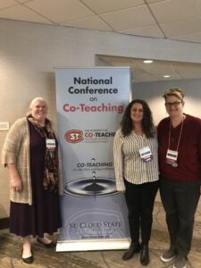 Drs. Maureen Grady, Charity Cayton and Christina Tschida take a photo with the National Conference on Co-Teaching banner.