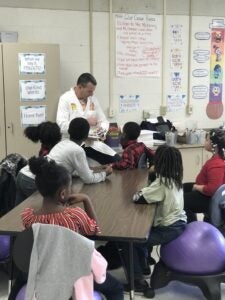 Dr. Robbie Quinn works with Pines Elementary School students on a CARE art project.