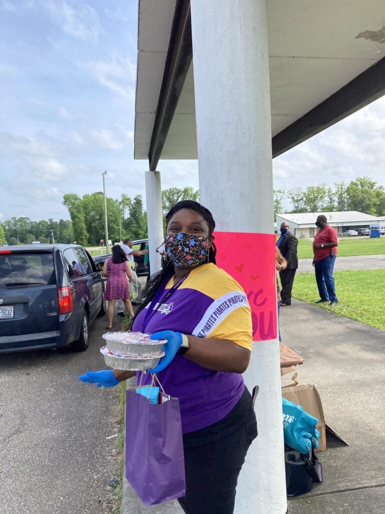 Jasmine Garland McKinney gets ready to hand a CARE package and personal pizza to a student at Pines Elementary.