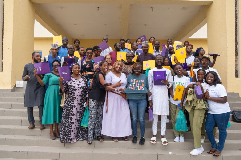 Group of people stand on steps holding ECU folders