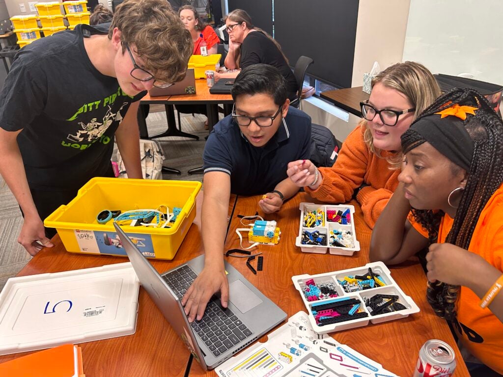 Students gather around a laptop