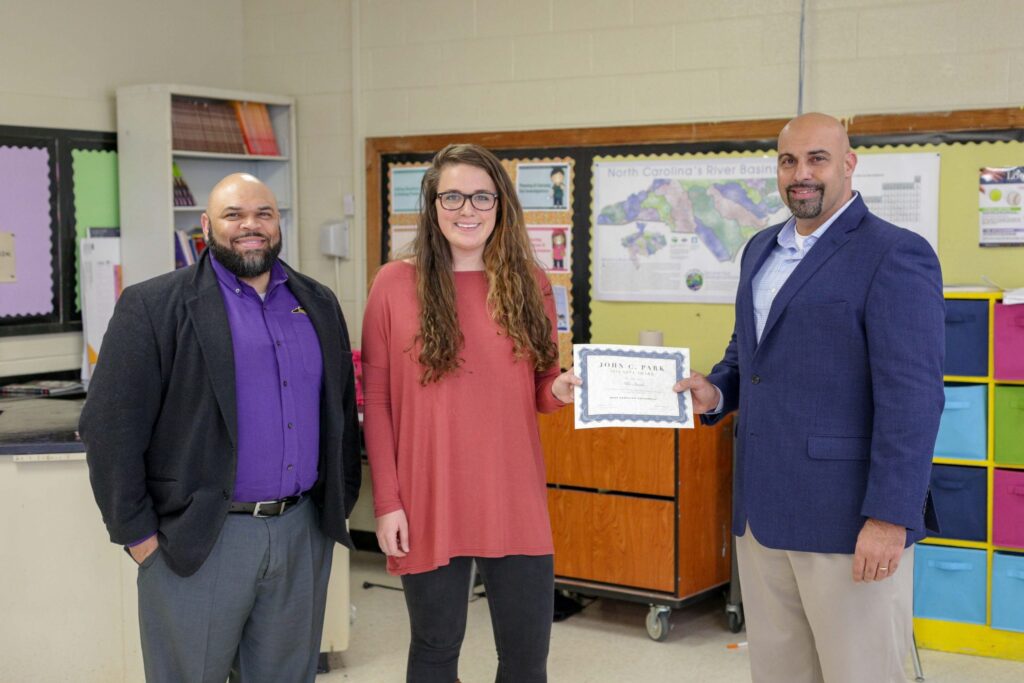 Dr. Leonard Annetta, right, and Shawn Moore, left, presents eighth-grade C.M. Eppes Middle School teacher Allie Smith with the inaugural John C. Park Scholarship Thursday, March 8. 