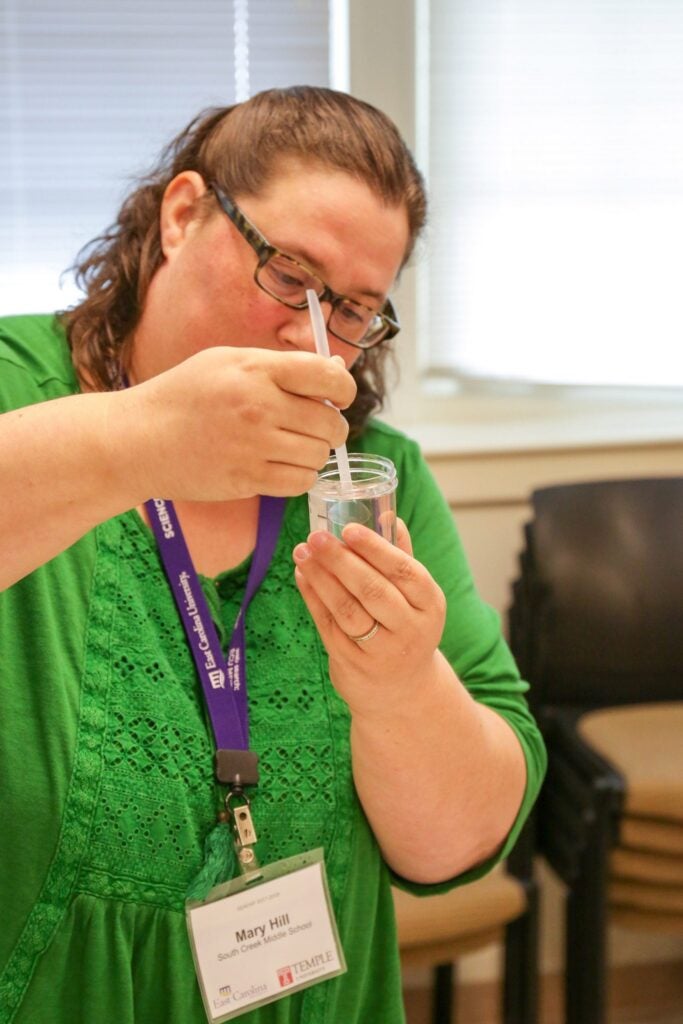 Hill picks up a planarian to place it in a solution of highly diluted nicotine. 