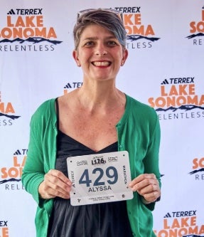 woman holding a racing bib in front of Lake Sonoma logo backdrop