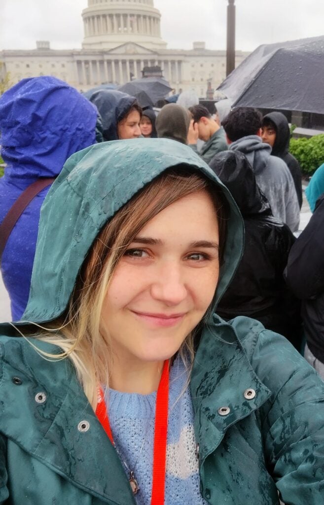woman wearing a raincoat standing in a crowd in front of the US Capitol building