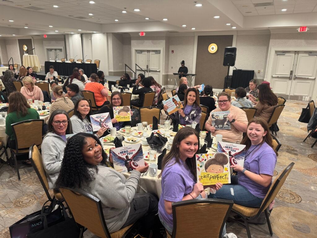 female students sit around a table holding books in their hands