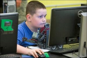  Logan Chase, 10, works on programming after a practice session with his robot.