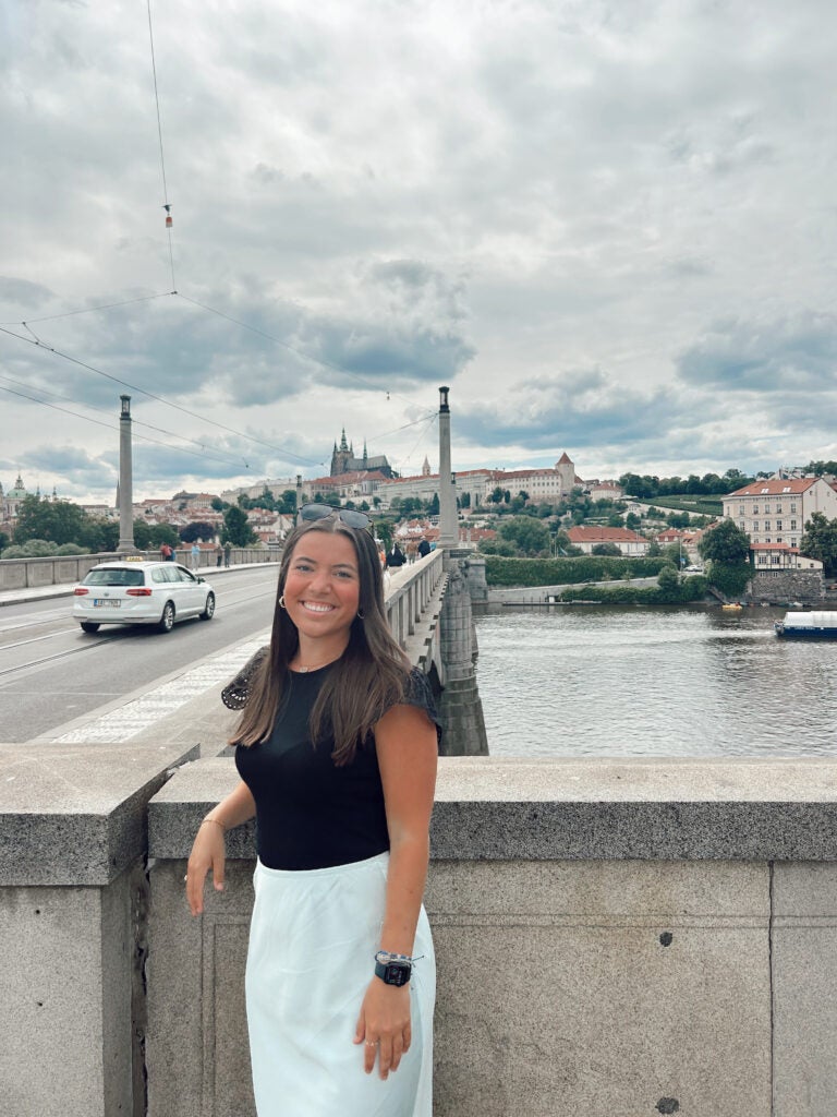 female student standing on a bridge overlooking city landscape