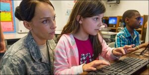 Amy Perry, left, watches as her daughter, Kayla Perry, works at the Operation LINK afterschool program held this spring in Goldsboro. Amy Perry is a technical sergeant in the U.S. Air Force, where she inspects aircraft for defects at Seymour Johnson Air Force Base.