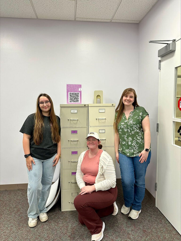 three female students gathered around two file cabinets