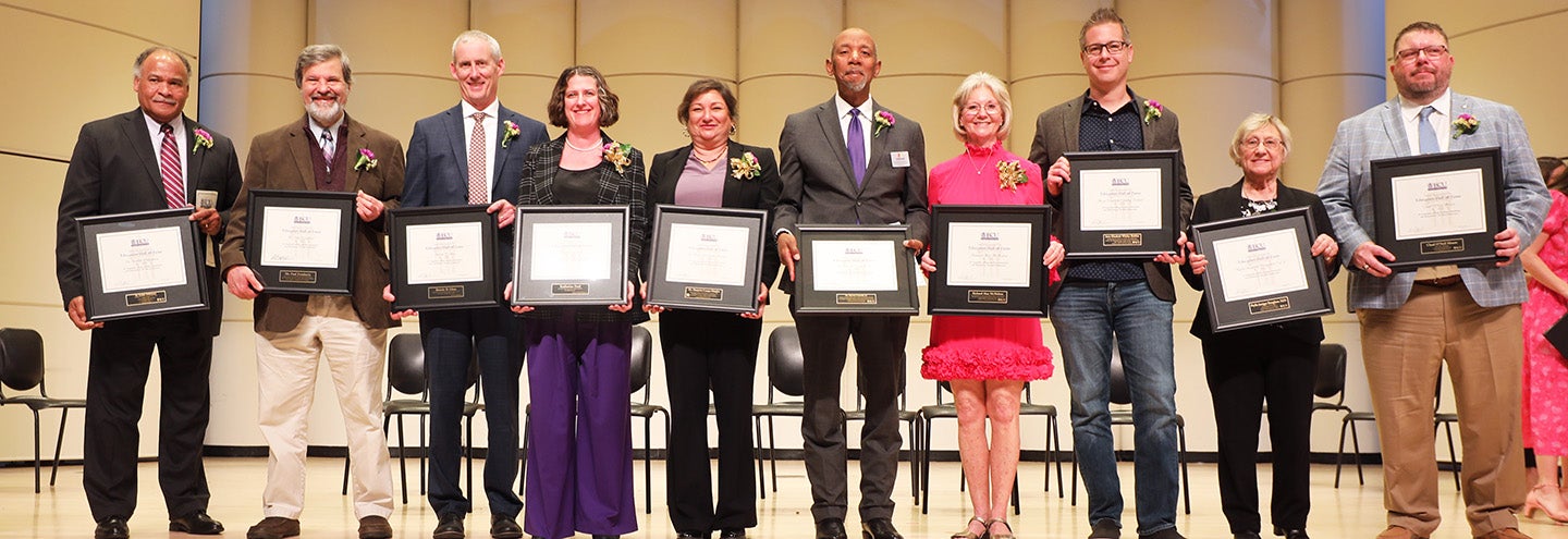 10 educators standing in a line holding their EHOF induction plaques